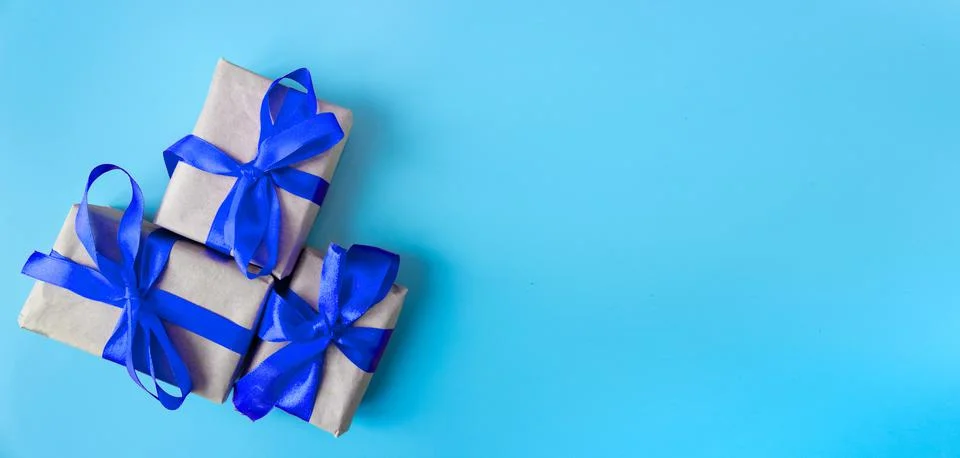 Gift boxes with a blue bow on a blue background. Banner. Copy space. Stock Photos