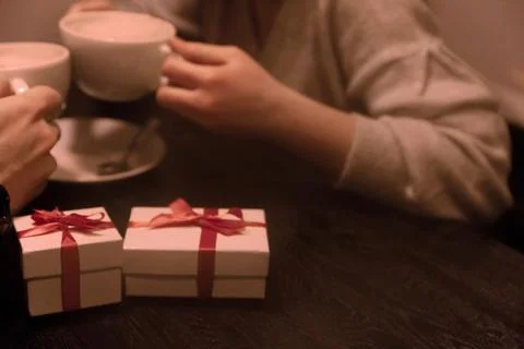 Gift Boxes on Coffee Background in Hands of Men and Women Stock Photos