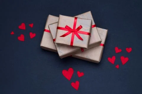 Gift boxes decorated with red ribbons with bows lie on a black background Stock Photos