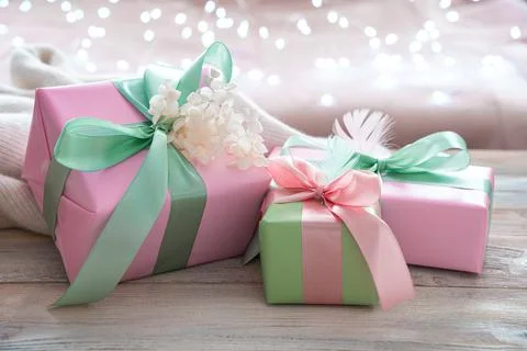 Gift boxes of delicate flowers on a light background with a burning garland. Stock Photos