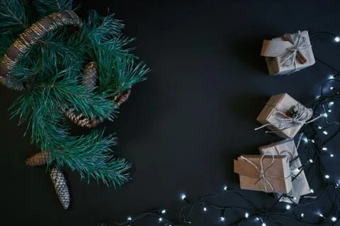 Gift boxes, garland and basket with christmas tree branches on dark background. Stock Photos