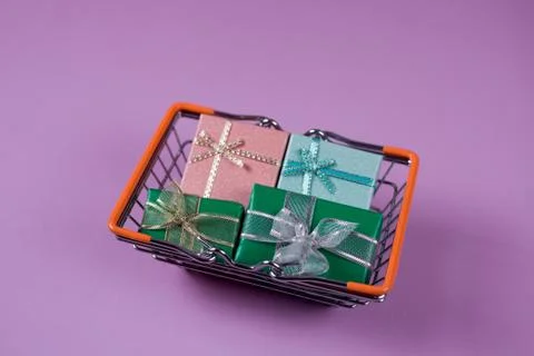 Gift boxes inside the shopping cat on the violet background. Stock Photos