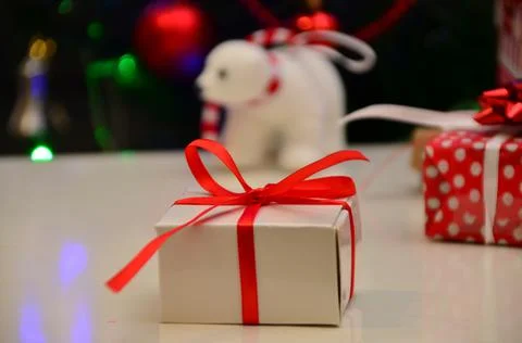 Gift boxes with a large red bow against a background bokeh of twinkling party Stock Photos