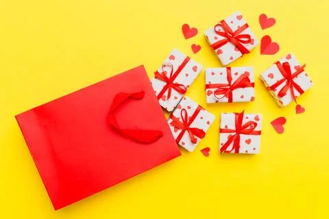 Gift boxes pop out from paper bag top view on colored background. bag packing Stock Photos
