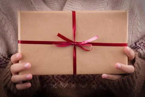 Gift boxes with red ribbon in the hands. Hands hold gifts in craft paper Stock Photos