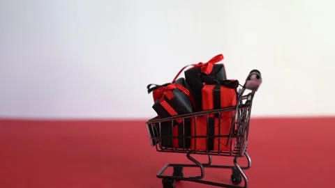 Gift boxes in shopping cart on red and white background, . black friday Stock Footage 219550282