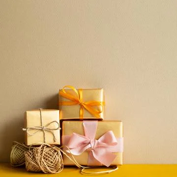Gift boxes with string thread reel on wooden table with beige background Stock Photos