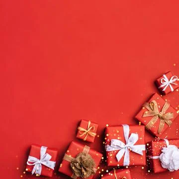 Gift boxes with white and brown bows on a red backdrop. Stock Photos