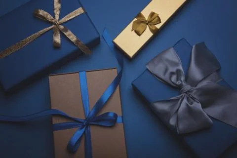 Gift boxes wrapped in classic blue paper with a gold, blue and grey ribbons. Stock Photos
