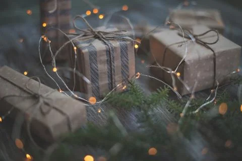 Gift boxes wrapped in craft paper, fir branches and garland lights. Fotos de archivo