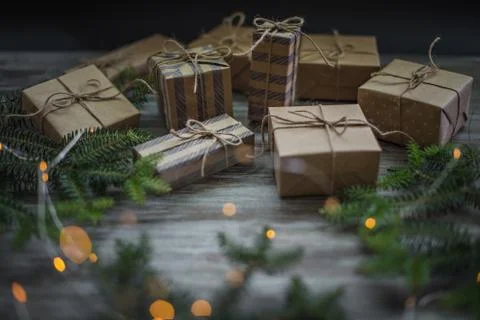 Gift boxes wrapped in craft paper, fir branches and garland lights. Fotos de archivo