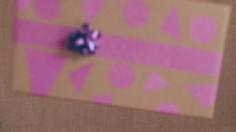 Gift boxes wrapped in gift paper fall on the table. Human hand takes a gift Stock Footage 252062770