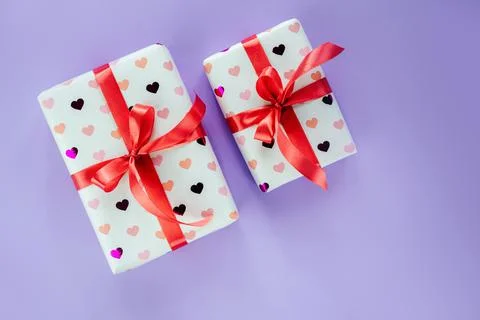 Gift boxes wrapped in heart pattern paper with red ribbon bow on pink background Stock Photos
