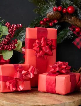 Gift boxes wrapped in red paper against Christmas decor background Stock Photos