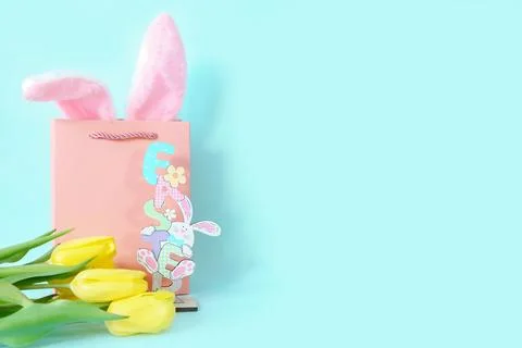 Gift card with Easter figurine, rabbit ears in a pink bag and yellow tulips. Stock-Fotos
