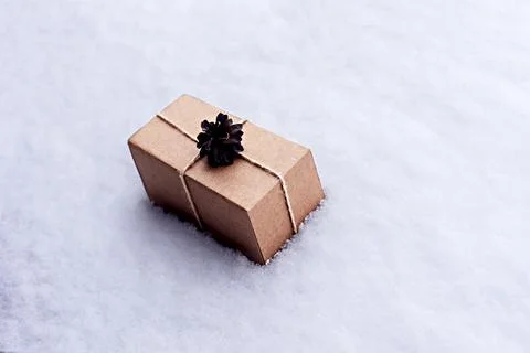 Gift in craft box decorated with pine cone on white snow, eco friendly concept Stockfoto's