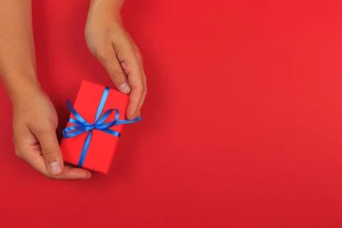 Gift in female hands on a colored background top view. Stock Photos
