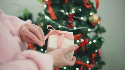 Gift giving by a decorated Christmas tree with red ribbons and ornaments during Stock Footage 329167541