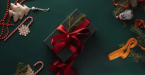 Gift in green packaging with red bow on green background with Christmas tree Stock Photos
