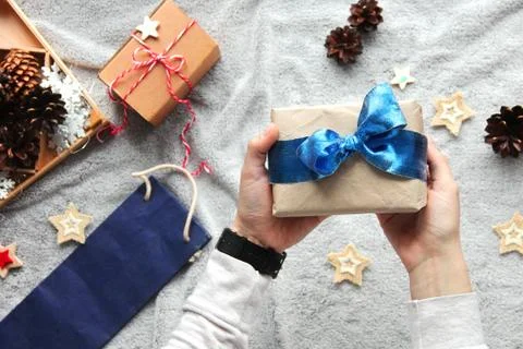 Gift in hand. Gift wrapping process. Blue bow. Gifts in craft paper Stock Photos