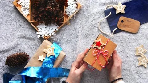 Gift in hand. Gift wrapping process. Blue bow. Gifts in craft paper Stock Photos