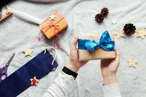 Gift in hand. Gift wrapping process. Blue bow. Gifts in craft paper Stock Photos