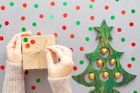Gift in hands, confetti on a gray background. Stock Photos
