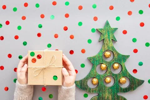 Gift in hands, confetti on a gray background. Stock Photos