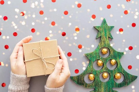 Gift in hands, confetti on a gray background. Stock Photos