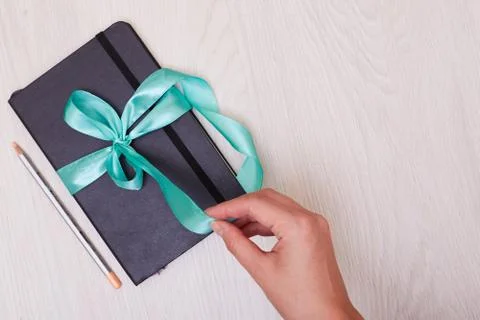 Gift notepad with ribbon on the table. Pencil and sketchbook. Stock Photos