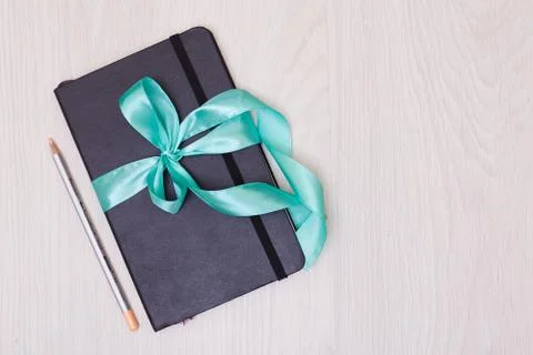 Gift notepad with ribbon on the table. Pencil and sketchbook. Stock Photos