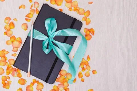 Gift notepad with ribbon on the table. Pencil and sketchbook. Stock Photos