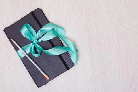 Gift notepad with ribbon on the table. Pencil and sketchbook. Stock Photos