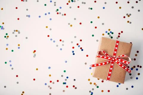 Gift or gift box and confetti on the white table on top. Flat arrangement for Stock Photos