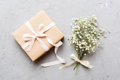 Gift or present box and flower gypsophila on light table top view. Greeting c Stock Photos
