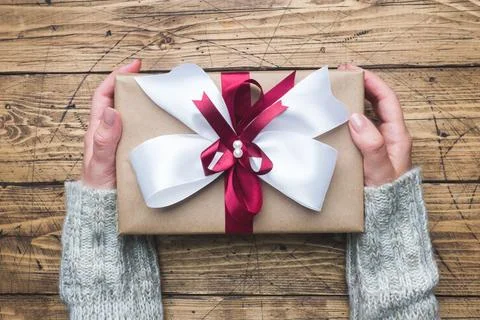 Gift or present box with a big bow in the hands of a woman in a sweater. Fl.. 스톡 사진