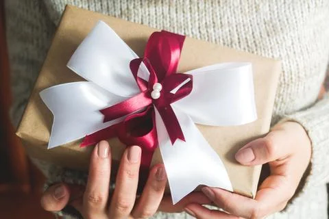 Gift or present box with a big bow in the hands of a woman in a sweater. co.. 스톡 사진