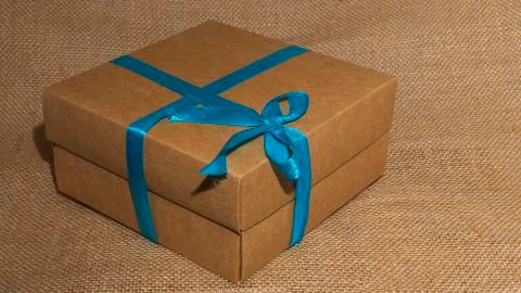 Gift or present box with blue ribbon on sackcloth background. Space fot text. Stock-Fotos