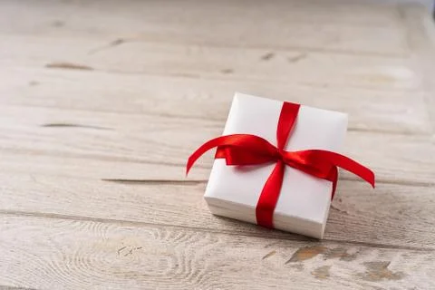 Gift or present box with red bow on wooden background. Pastel colors, copy space Stock Photos
