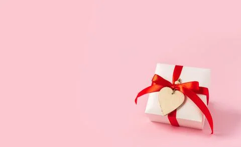 Gift or present box with red bow and heart on pink background. Pastel colors Stock Photos