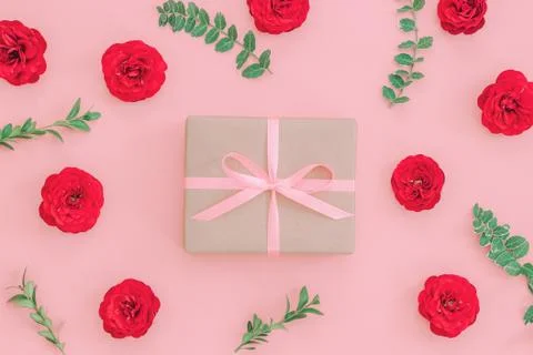 Gift or present box wrapped in kraft paper and rose flower on pink table top Stock Photos