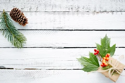 Gift in package, conifer branch, guilder leaves and berries over wooden bac.. Stock Photos