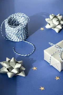 Gift packaging: silver bows for gift decoration, blue gift rope, gift in a si Stock Photos