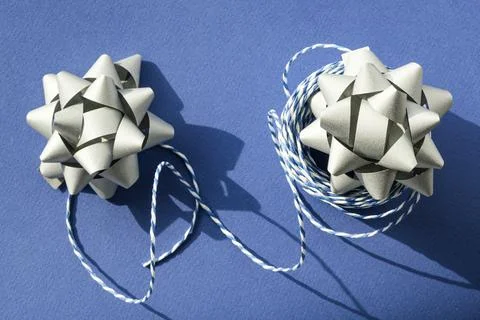 Gift packaging: silver bows for gift decoration and blue gift rope on a blue Stock Photos