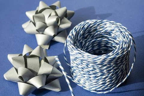 Gift packaging: silver bows for gift decoration and blue gift rope on a blue Stock Photos