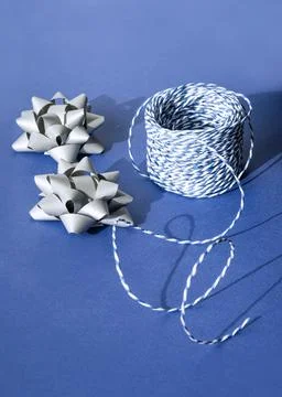 Gift packaging: silver bows for gift decoration and blue gift rope on a blue Stock Photos