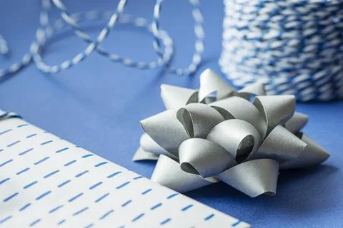Gift packaging: silver bows for gift decoration, blue gift rope, gift in a wh Stock Photos