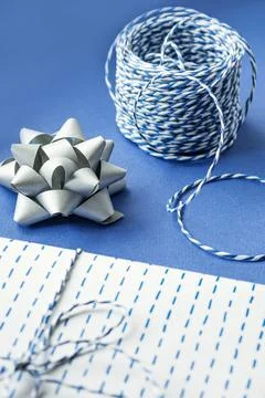 Gift packaging: silver bows for gift decoration, blue gift rope, gift in a wh Stock Photos