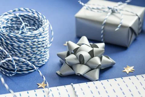 Gift packaging: silver bows for gift decoration, blue gift rope, gift in a wh Stock Photos