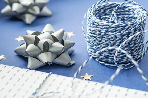 Gift packaging: silver bows for gift decoration, blue gift rope, gift in a wh Stock Photos